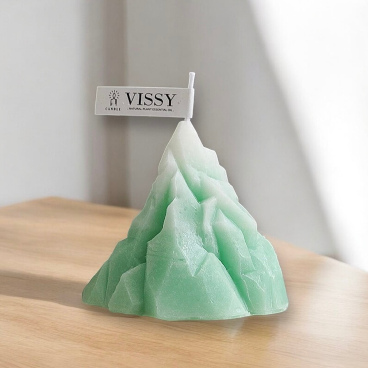 Mint green ombre mountain shaped scented candle on a wooden table