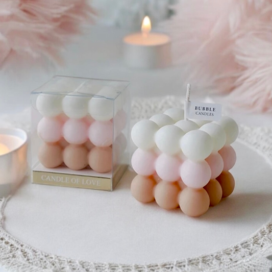 Pink ombre bubble cube scented candle with white, pink and tan layers beside its gift box