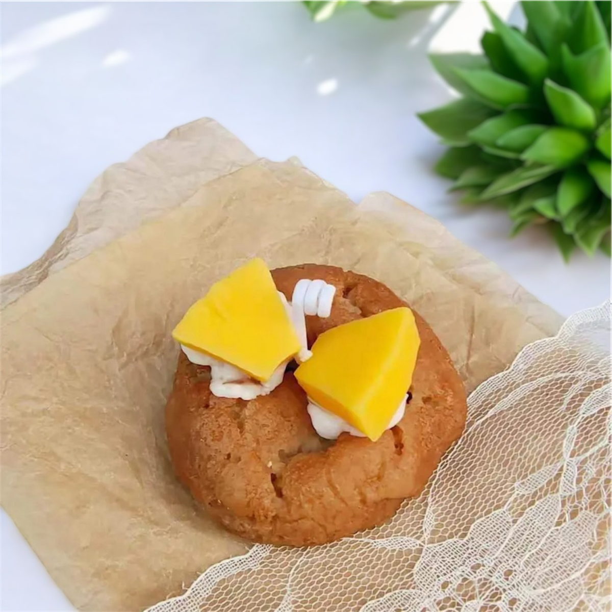 Golden cookie scented candle topped with mango pineapple pieces on parchment