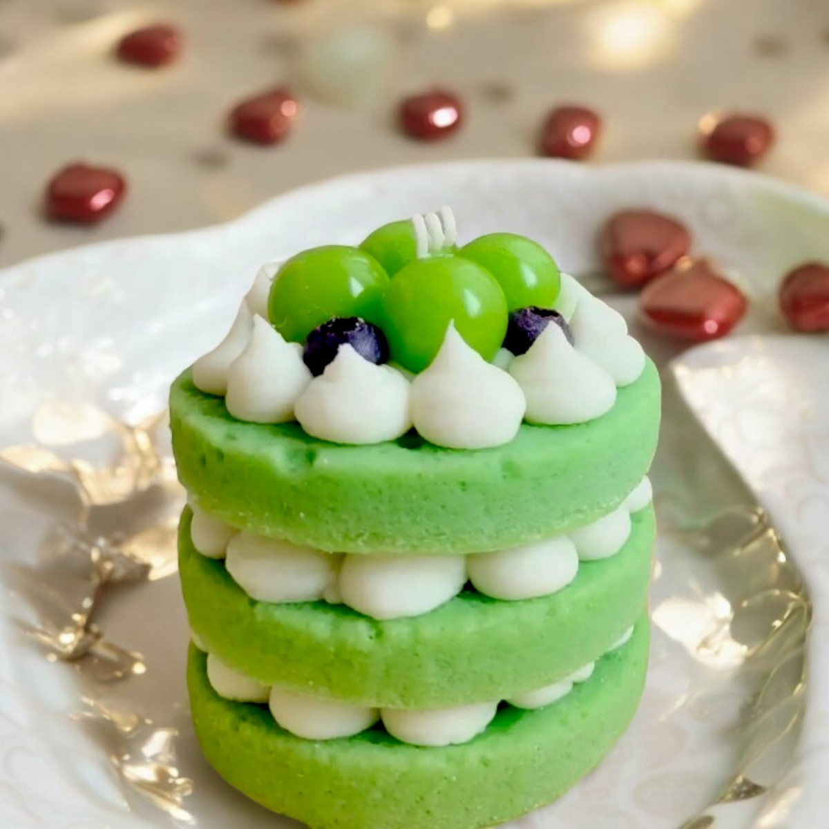 Green three layer cake scented candle topped with green grapes and cream swirls