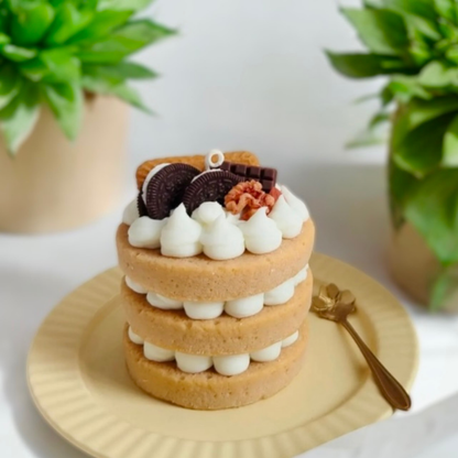 Light brown three layer cake scented candle topped with a chocolate sandwich cookie