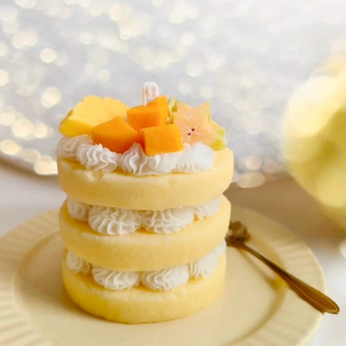 Yellow three layer cake scented candle topped with mango cubes and star fruit