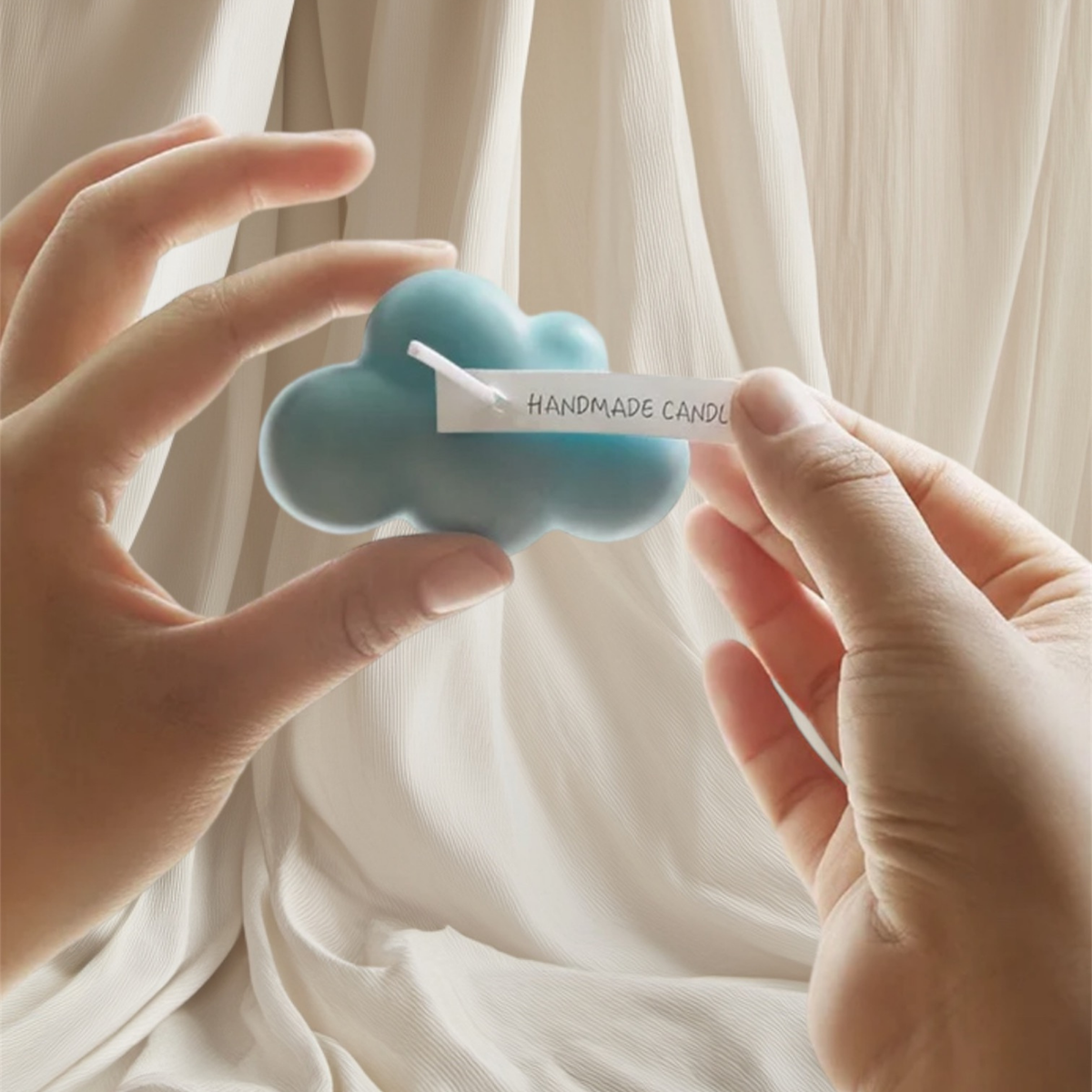 Hands holding a baby blue cloud shaped scented candle
