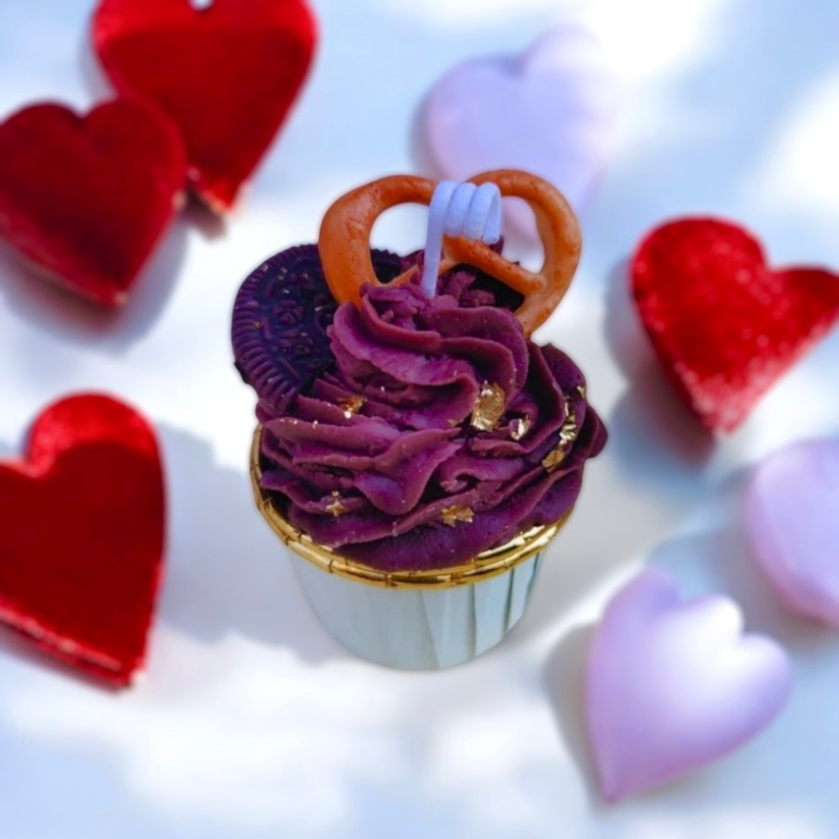 Purple frosted cupcake scented candle with a pretzel and gold flecks