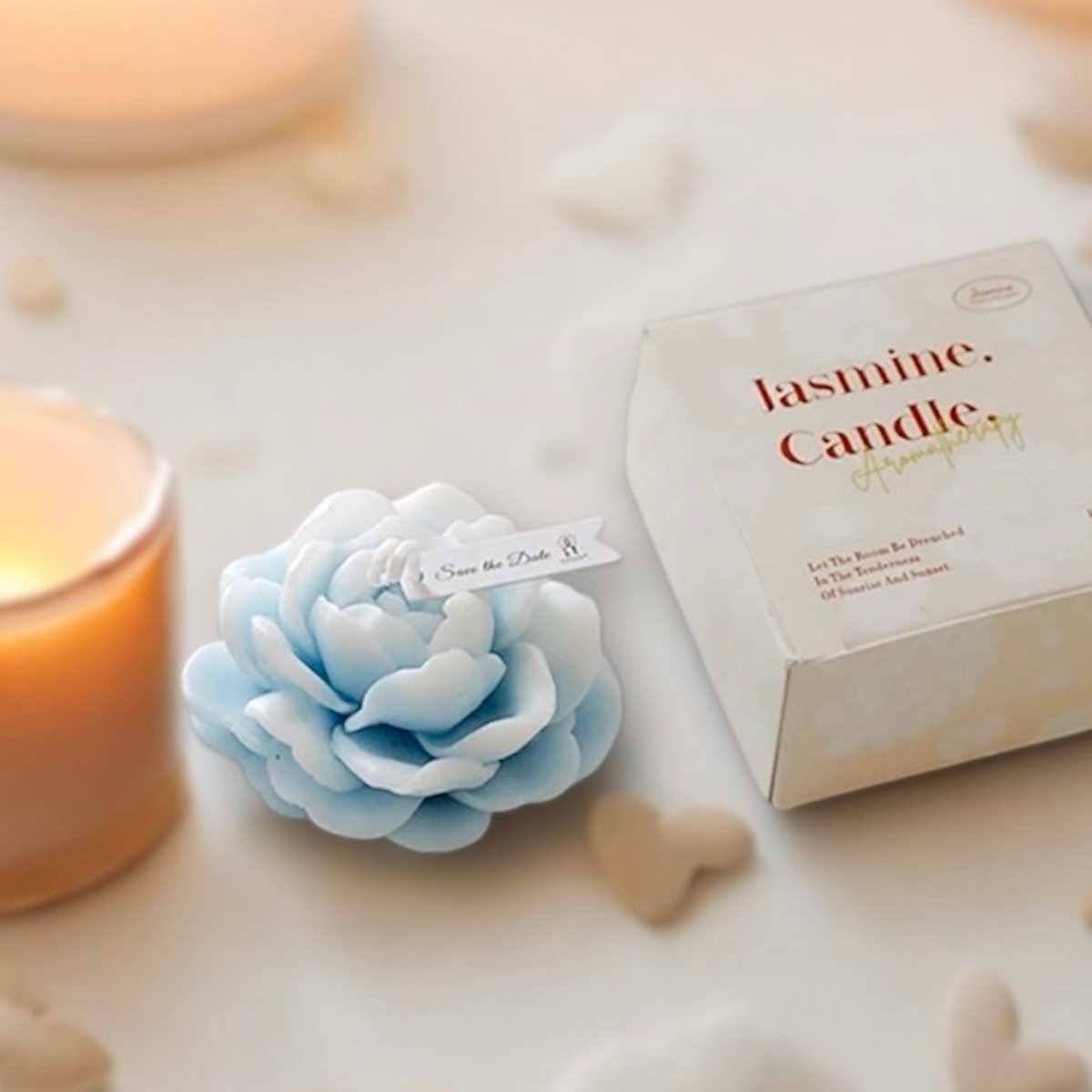 Baby blue peony flower scented candle with gift box and a lit candle behind