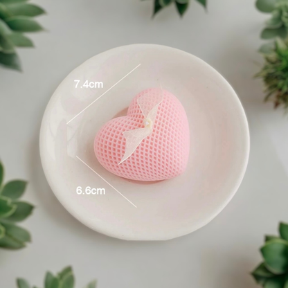 Light pink waffle textured heart scented candle on a dish, 7.4 cm by 6.6 cm