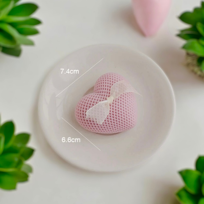 Pink heart scented candle with a white bow on a dish