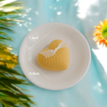 Yellow waffle textured heart scented candle on a dish, 7.4 cm by 6.6 cm