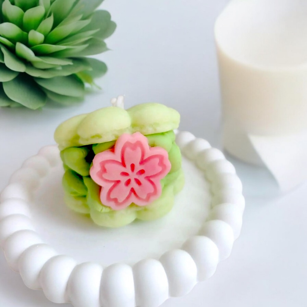 Green matcha macaron scented candle with a pink sakura flower