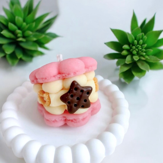Pink macaron scented candle with a chocolate star filling on a white dish