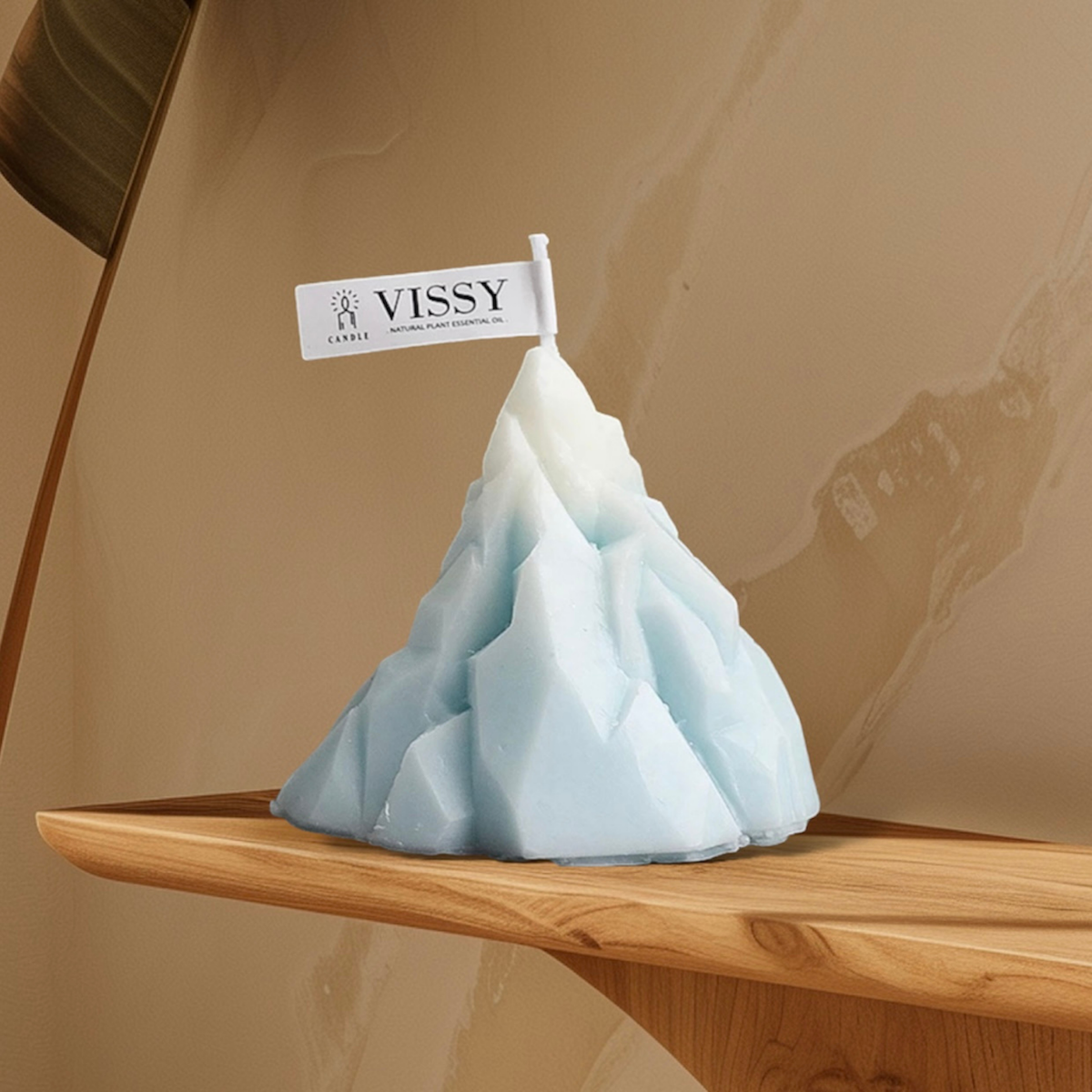 Light blue iceberg mountain shaped scented candle on a wooden shelf
