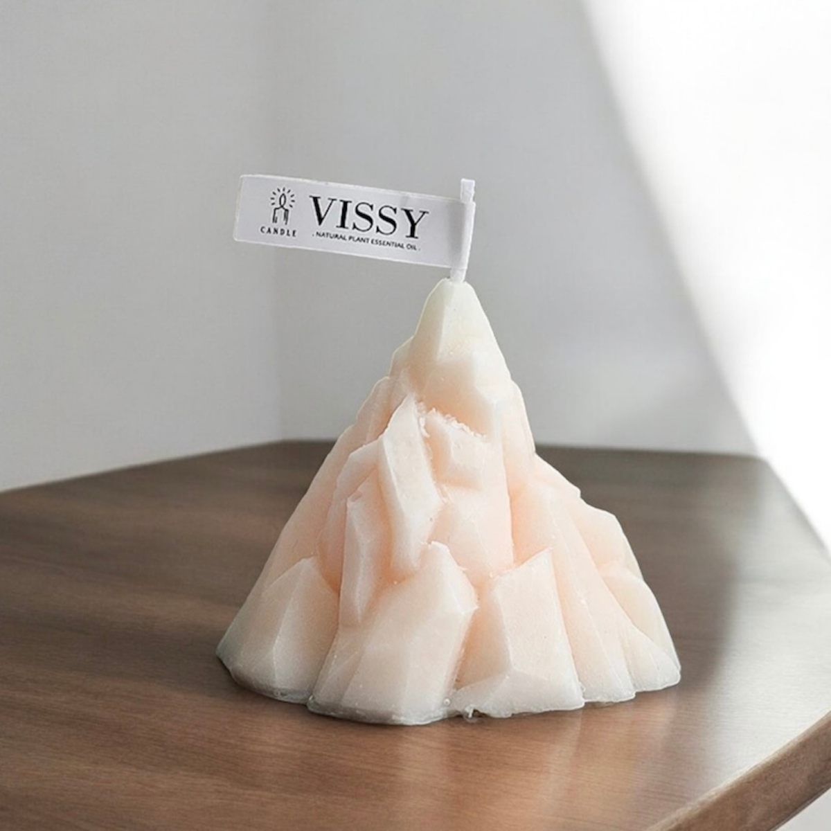 Light pink peach mountain shaped scented candle on a wooden table