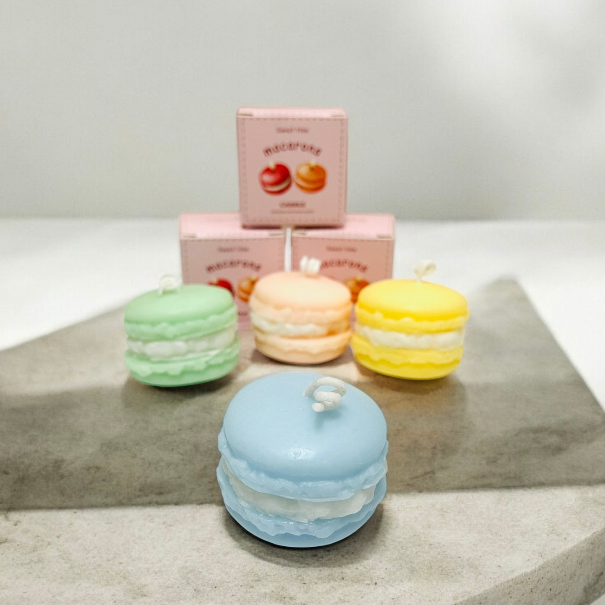 Baby blue, green, peach and yellow macaron scented candles on a stone slab