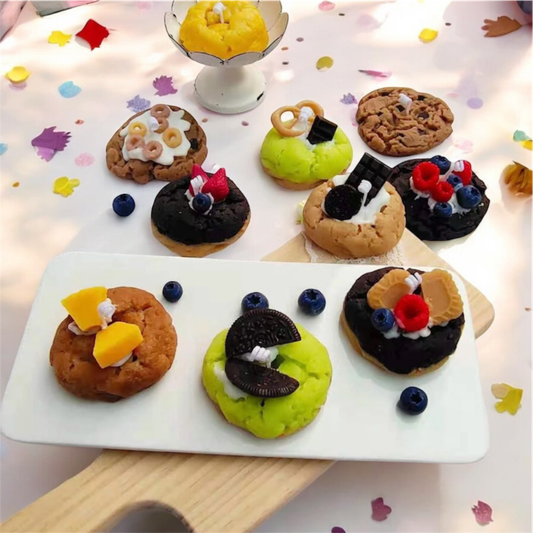 Nine assorted mini cookie and donut scented candles arranged on a white tray