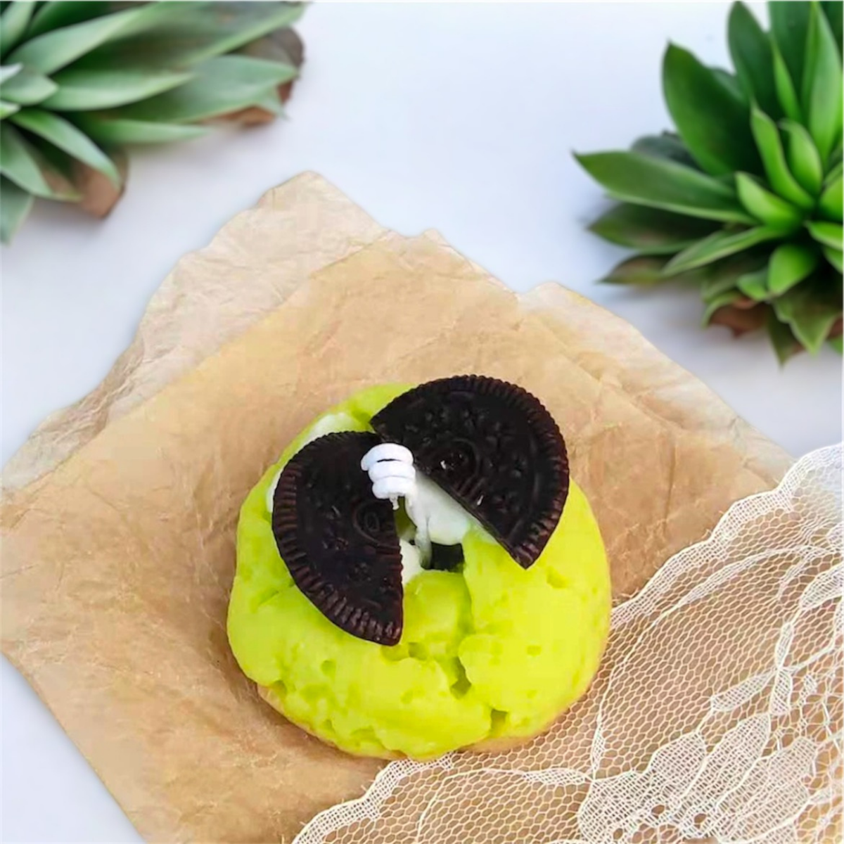 Green matcha cookie scented candle with two chocolate sandwich biscuit halves