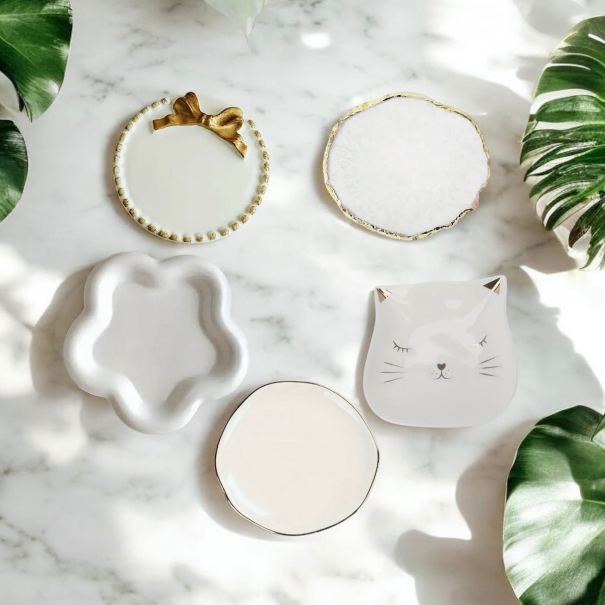 Five ceramic candle plate styles on white marble with tropical leaves