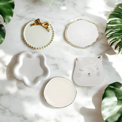 Five ceramic candle plate styles on white marble with tropical leaves