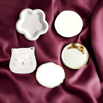 Five ceramic candle plate styles arranged on burgundy satin