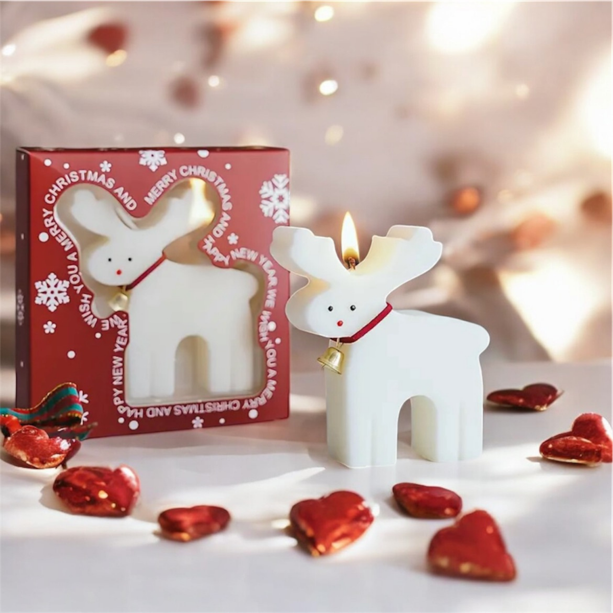 Lit white reindeer scented candle beside its red Merry Christmas gift box