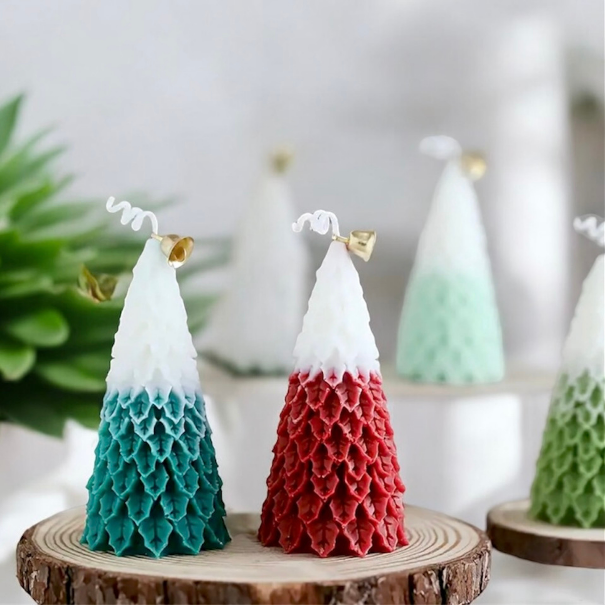 Teal and red ombre Christmas tree scented candles on wood slices with greenery