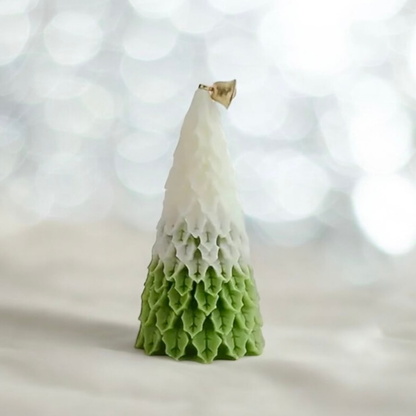 Green ombre Christmas tree scented candle with gold bell against bokeh lights