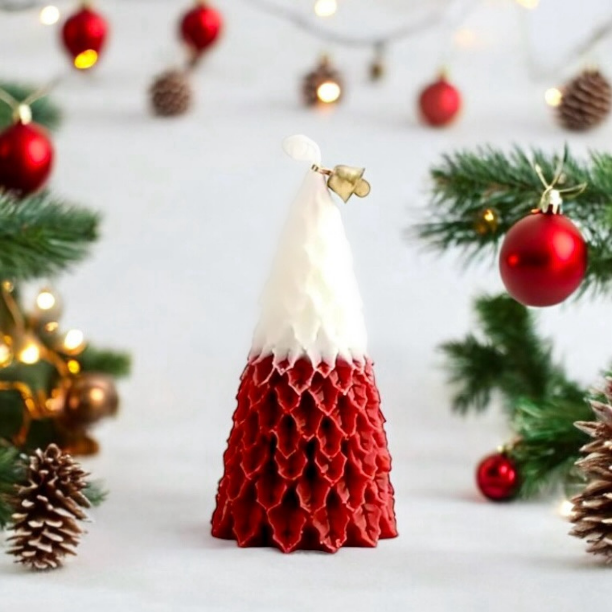 Red and white Christmas tree scented candle with baubles, pine and pine cones